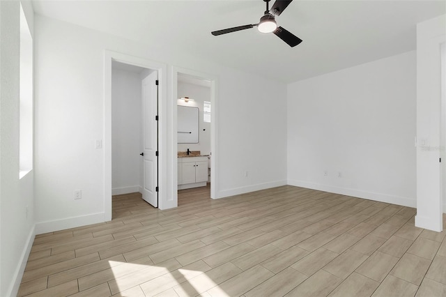 unfurnished bedroom featuring light wood-style flooring, a spacious closet, baseboards, and ceiling fan