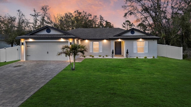 ranch-style house with an attached garage, a lawn, fence, and decorative driveway