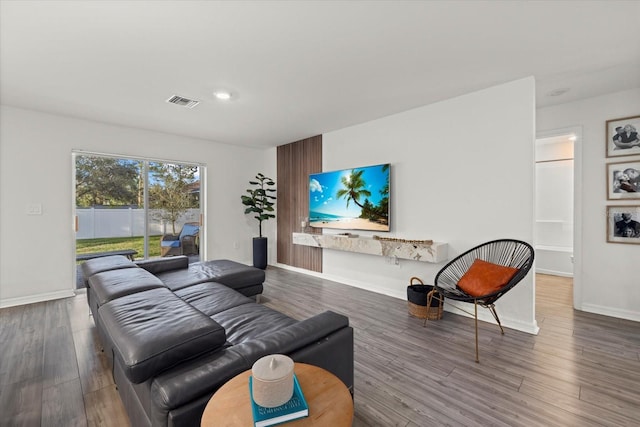 living room with wood finished floors, visible vents, and baseboards