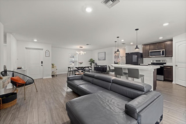 living room with light wood-style floors, recessed lighting, visible vents, and baseboards