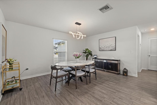 dining space featuring an inviting chandelier, baseboards, visible vents, and wood finished floors