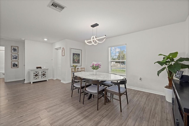 dining area featuring a notable chandelier, wood finished floors, visible vents, and baseboards