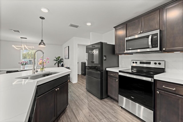 kitchen featuring appliances with stainless steel finishes, light countertops, visible vents, and a sink