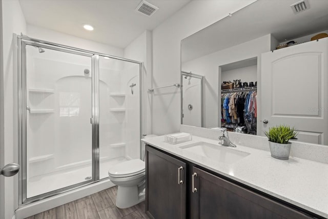 full bathroom with toilet, a stall shower, wood finished floors, and visible vents