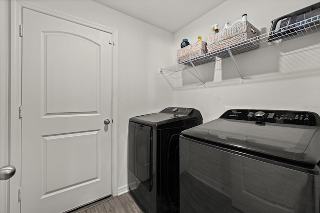 laundry room with laundry area, wood finished floors, and washing machine and clothes dryer