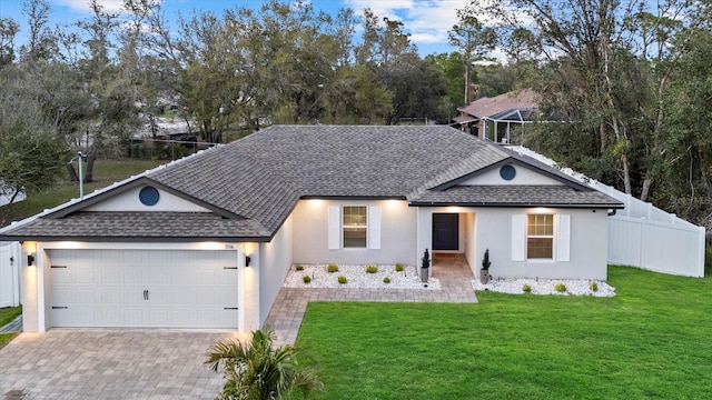 single story home featuring a garage, a shingled roof, fence, decorative driveway, and a front yard