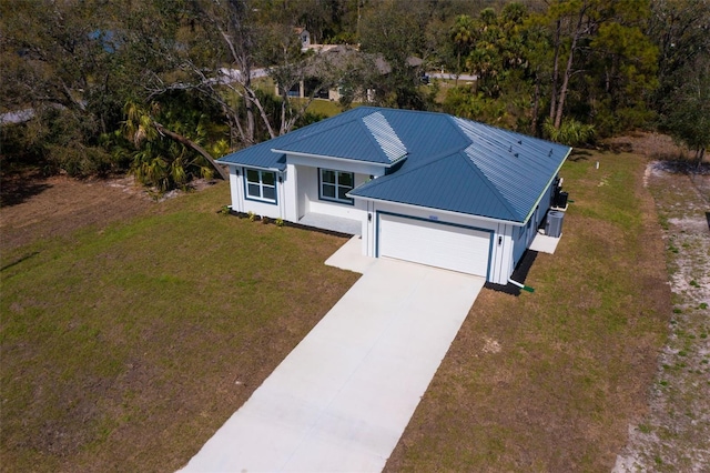 view of front of property with a garage, a front yard, concrete driveway, and metal roof