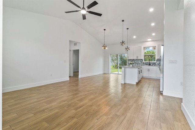 unfurnished living room featuring baseboards, a ceiling fan, light wood-style floors, high vaulted ceiling, and recessed lighting