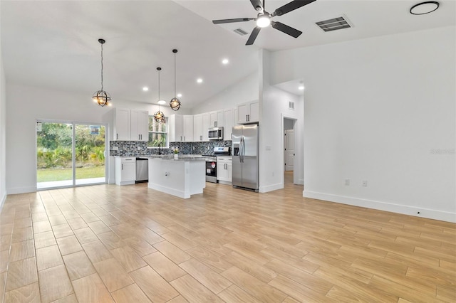 kitchen with light wood finished floors, tasteful backsplash, visible vents, appliances with stainless steel finishes, and open floor plan