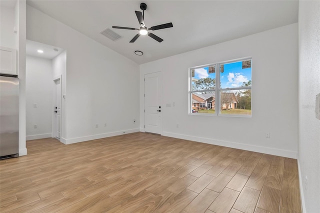 spare room with light wood-style flooring, a ceiling fan, visible vents, and baseboards