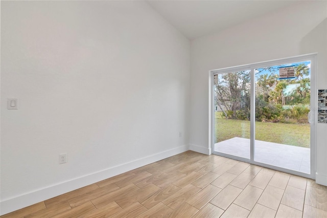 empty room with light wood-type flooring, baseboards, and vaulted ceiling