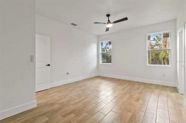 empty room with light wood-type flooring, baseboards, visible vents, and a ceiling fan