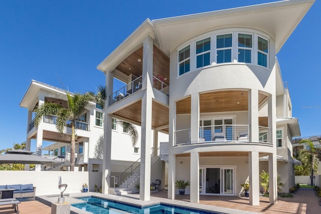 back of house with stucco siding, a patio, fence, stairway, and a fenced in pool