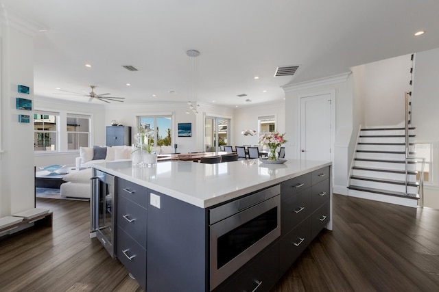 kitchen with beverage cooler, visible vents, a kitchen island, stainless steel microwave, and open floor plan