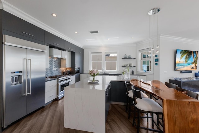 kitchen featuring dark cabinetry, modern cabinets, premium appliances, and ornamental molding