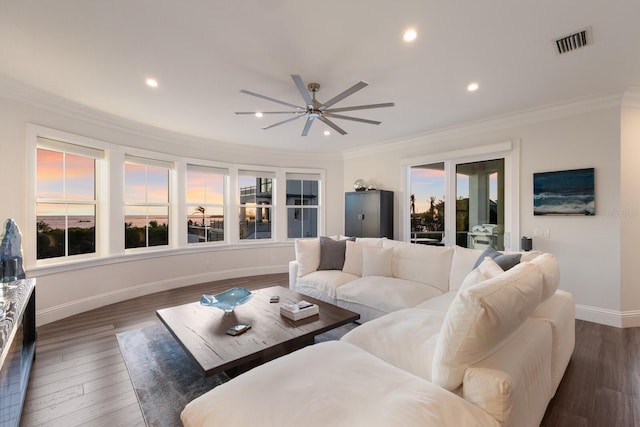 living area with visible vents, dark wood-style floors, crown molding, baseboards, and ceiling fan