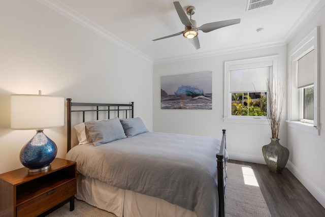 bedroom with visible vents, crown molding, baseboards, and wood finished floors