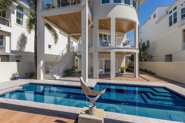 back of house with stucco siding, fence, stairway, a fenced in pool, and a patio area