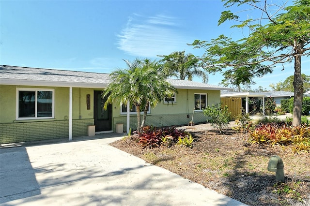 single story home with concrete driveway, brick siding, and stucco siding