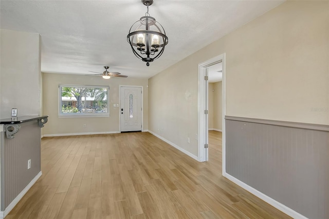 interior space with light wood-style floors, baseboards, and ceiling fan with notable chandelier