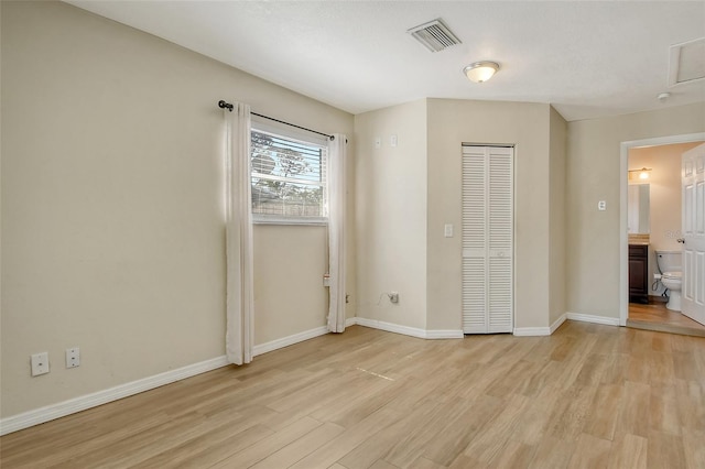 unfurnished bedroom featuring light wood-type flooring, baseboards, visible vents, and a closet