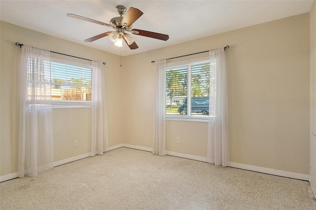 spare room featuring a ceiling fan and baseboards