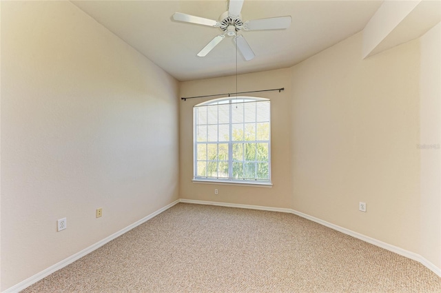 spare room with a ceiling fan, light carpet, and baseboards