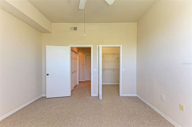 unfurnished bedroom featuring light carpet, baseboards, visible vents, and a walk in closet