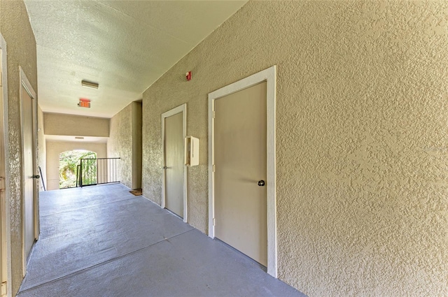 hall featuring a textured ceiling and concrete flooring