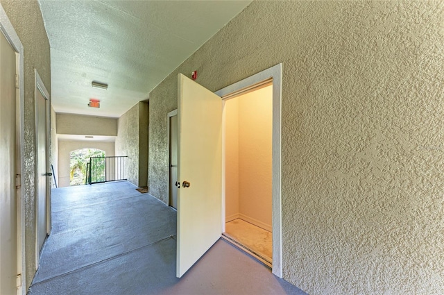 hallway with concrete floors and a textured ceiling