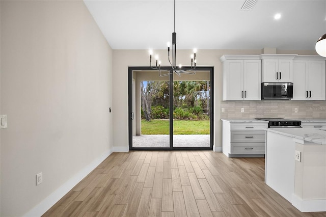 kitchen with light wood finished floors, stainless steel microwave, backsplash, range with electric cooktop, and visible vents