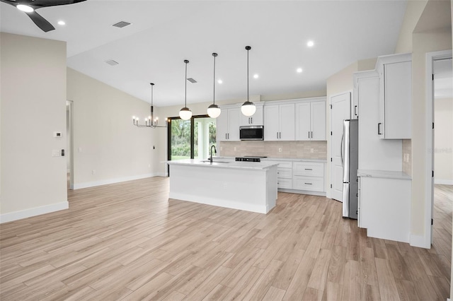 kitchen with light countertops, decorative backsplash, white cabinets, stainless steel appliances, and a sink