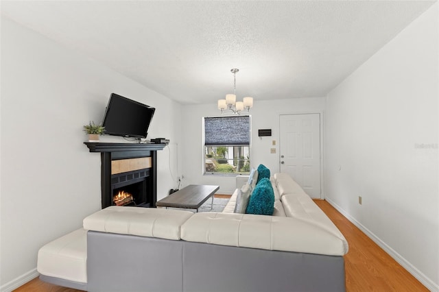 living area with a chandelier, a tile fireplace, wood finished floors, and baseboards