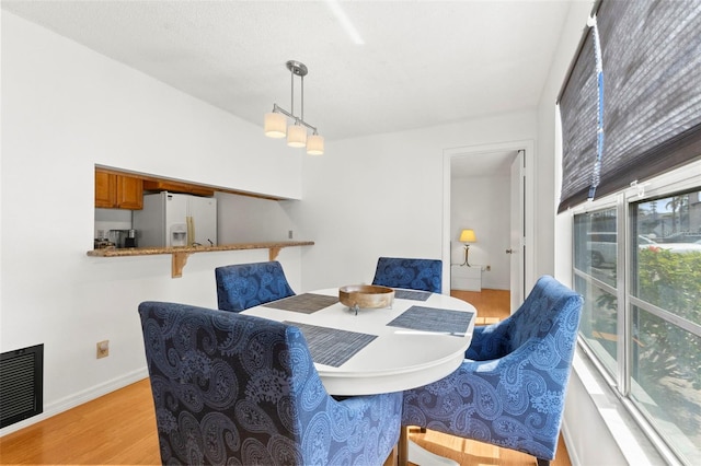 dining area featuring light wood-style flooring, visible vents, and baseboards