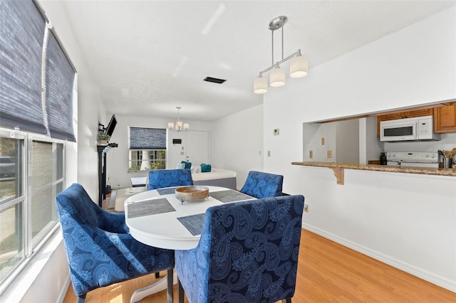 dining room featuring a chandelier, a textured ceiling, light wood-style flooring, and baseboards