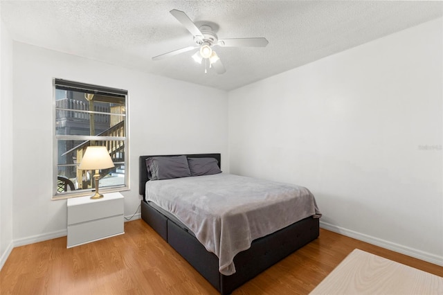 bedroom with a textured ceiling, baseboards, and wood finished floors