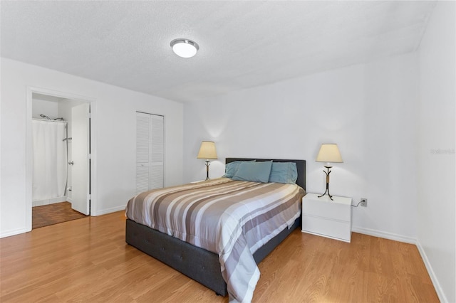 bedroom featuring baseboards, connected bathroom, wood finished floors, a textured ceiling, and a closet