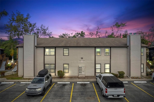 property at dusk featuring stairs and uncovered parking