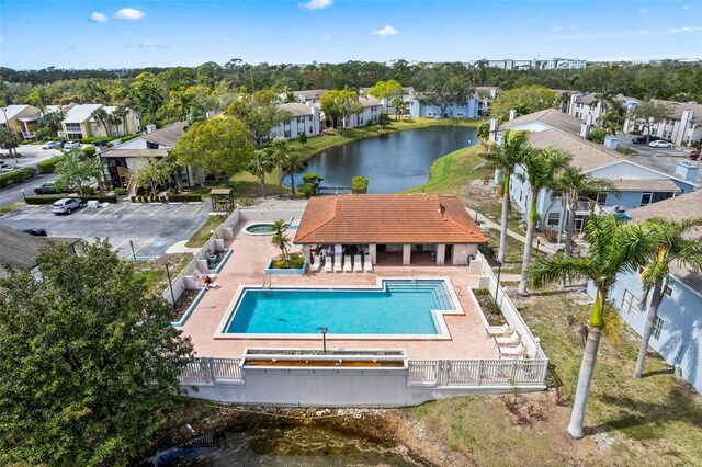 pool with a patio, a water view, fence, and a residential view