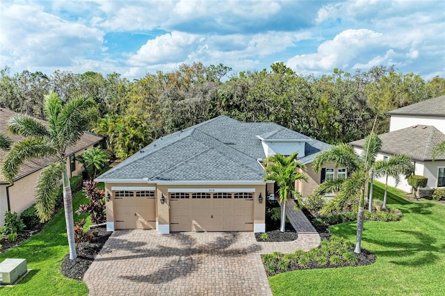 view of front of home with an attached garage, roof with shingles, decorative driveway, stucco siding, and a front lawn