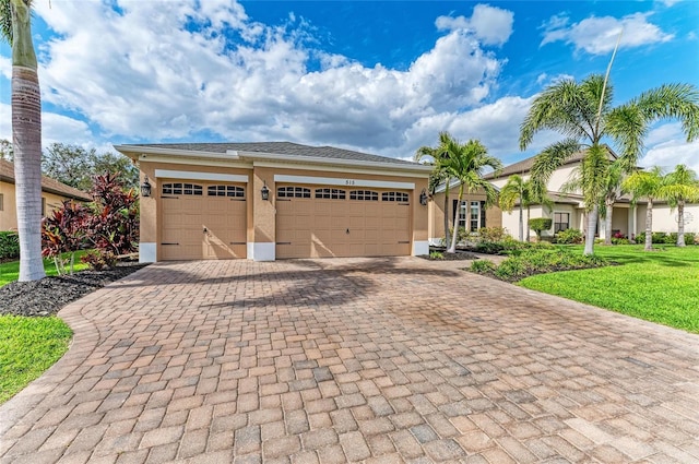 view of front of house with a garage, a front lawn, decorative driveway, and stucco siding