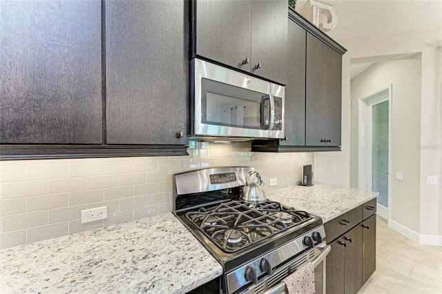 kitchen with appliances with stainless steel finishes, light stone countertops, baseboards, and tasteful backsplash