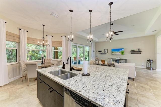 kitchen featuring a raised ceiling, open floor plan, an inviting chandelier, pendant lighting, and a sink