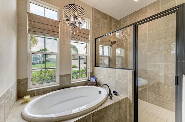 bathroom with a stall shower, a garden tub, and a notable chandelier