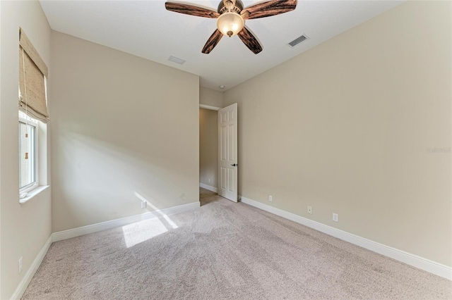 carpeted empty room featuring baseboards, visible vents, and ceiling fan