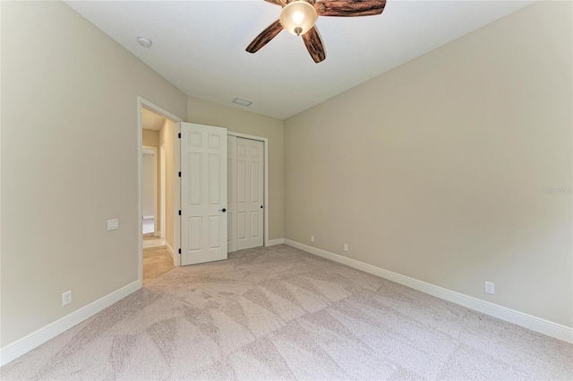 unfurnished bedroom with ceiling fan, baseboards, a closet, and light colored carpet