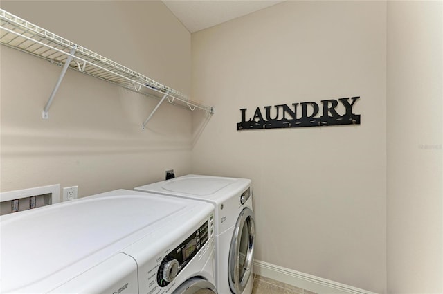 washroom featuring laundry area, baseboards, and washer and dryer