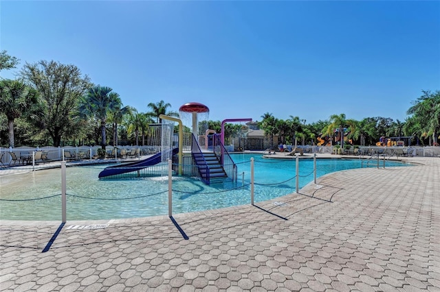 community pool with playground community, a water play area, and fence