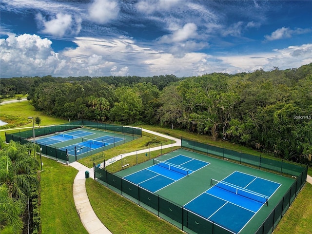 view of sport court with a forest view, fence, and a yard