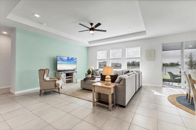 living room featuring light tile patterned floors, baseboards, ceiling fan, a tray ceiling, and recessed lighting